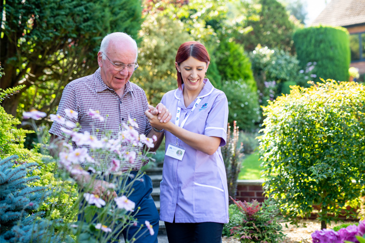 care professional and older person walking in the garden
