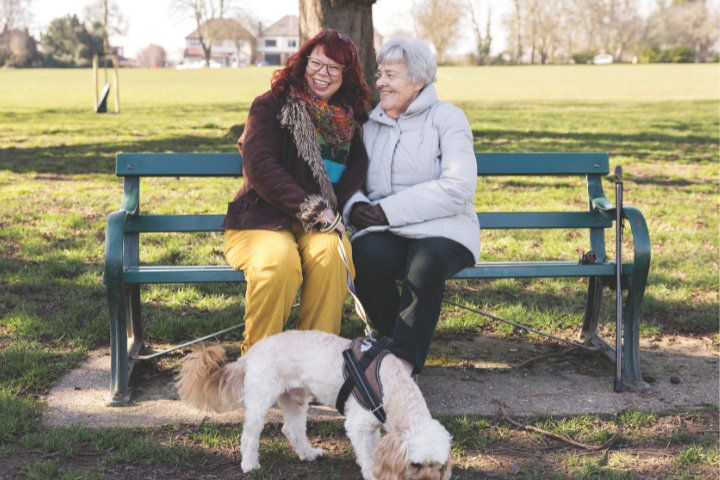 a client and live in carer out and about at the park sat on a bench after walking the dog