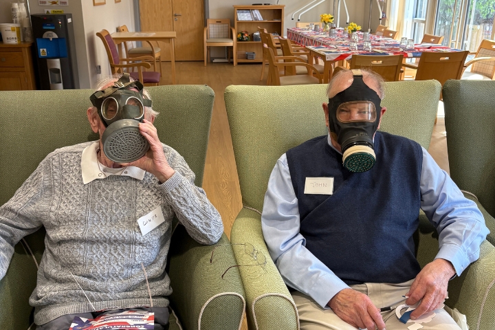 Day care centre member smiling while wearing a replica wartime gas mask during VE Day celebration in Chester.