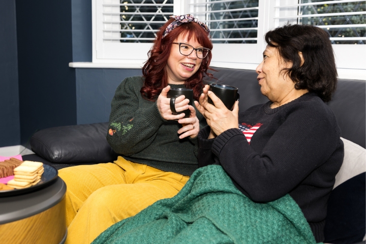 Care professional chatting with client over tea and biscuits
