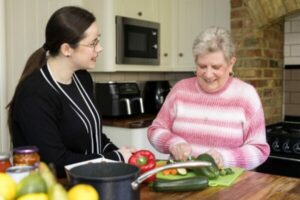 Healthy eating for older adults. Care professional helping a client cook a meal