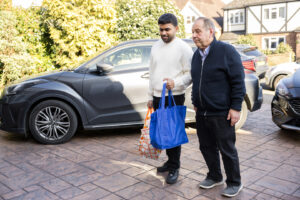 Picture of a Care Professional helping a client bring shopping into their home - sparking the "What if I'm not sure how much care is needed" thought. 