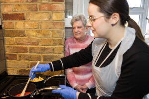 Care Professional cooking a meal for a client - showing the value of live in care at home